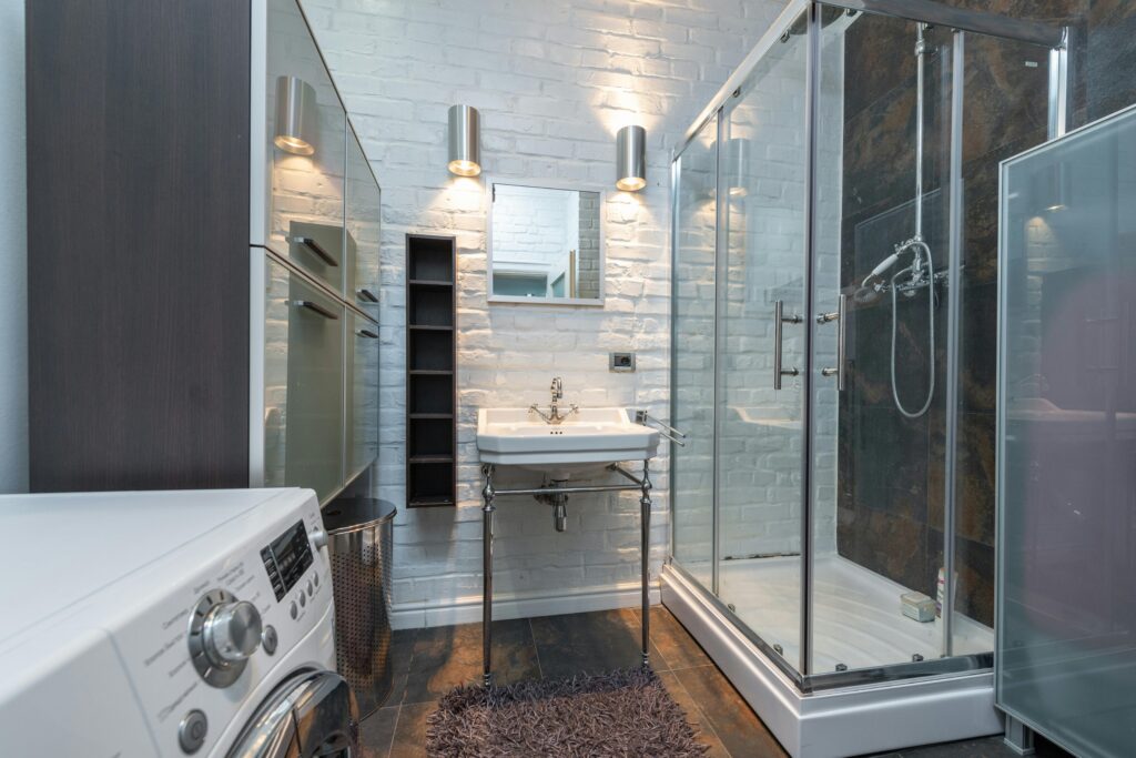 Sleek and contemporary bathroom showcasing a shower cabin, sink, and washing machine.